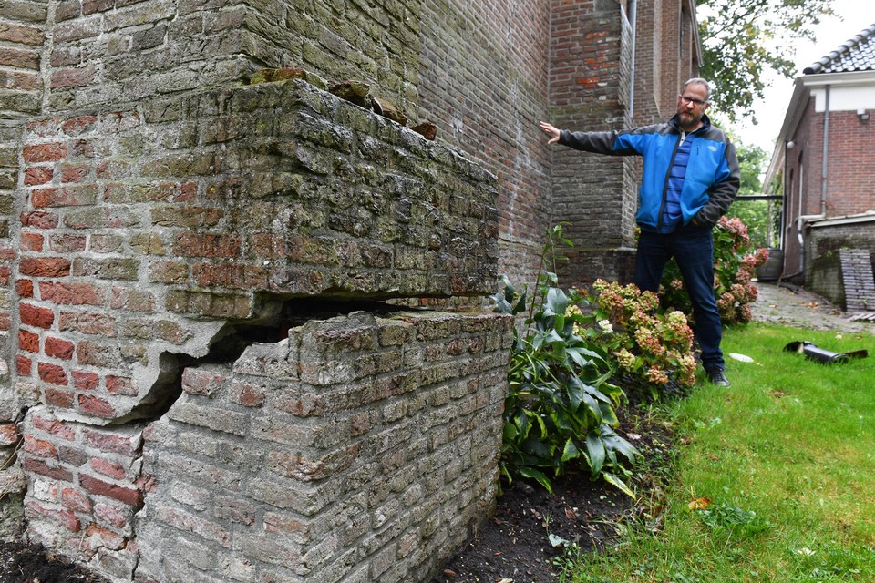 Een enorme scheur is te zien in een steunbeer aan de buitenkant van de kerk. Op de achtergrond bestuurslid Martijn Jansen.