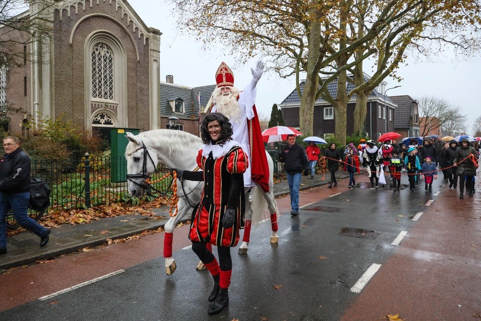 Sinterklaas rijdt, begeleid door zijn roetveegpiet, door het dorp.