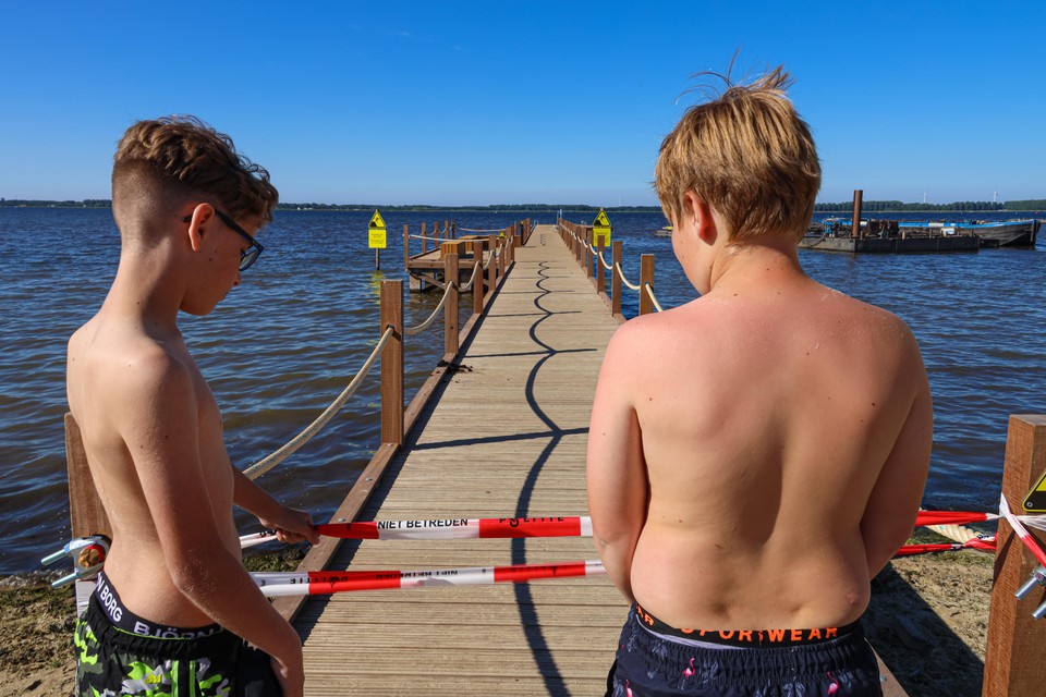 Beteuterd kijken Kay en Luuk naar het rood/witte lint dat moet voorkomen dat zwemmers gebruik maken van de nieuwe zwemsteiger.