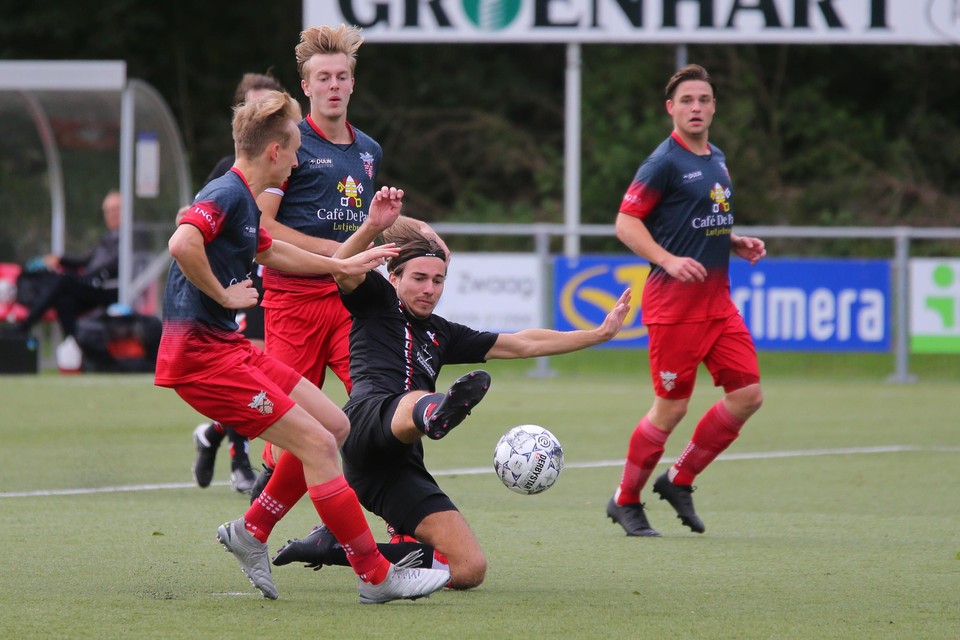 HBS-spelers Boris van den Berg glijdt naar de bal. Brian Sikkens (links), Noah Marsman (midden) en Thijs Jansen van De Zouaven kijken toe.
