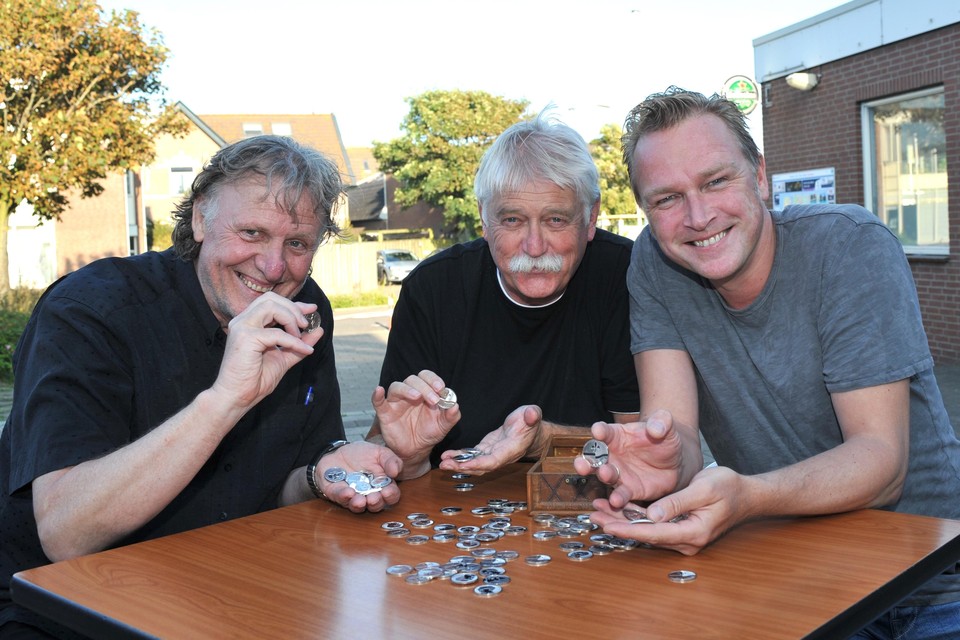 De initiatiefnemers Jan van der Land, Aart Hiemstra en Fons Heine (vlnr) laten de munt zien met de beeltenis van Han van Leeuwen erop.