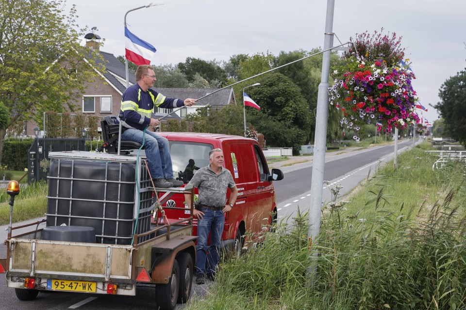 Vrijwilligers Theo Blokker (l.) en Gé Leurs geven de bloemen op de Middenweg water.