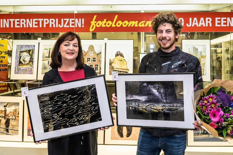 Daan van Asselt met zijn twee winnende foto’s. Links Karin Verdel die de wedstrijd organiseerde.