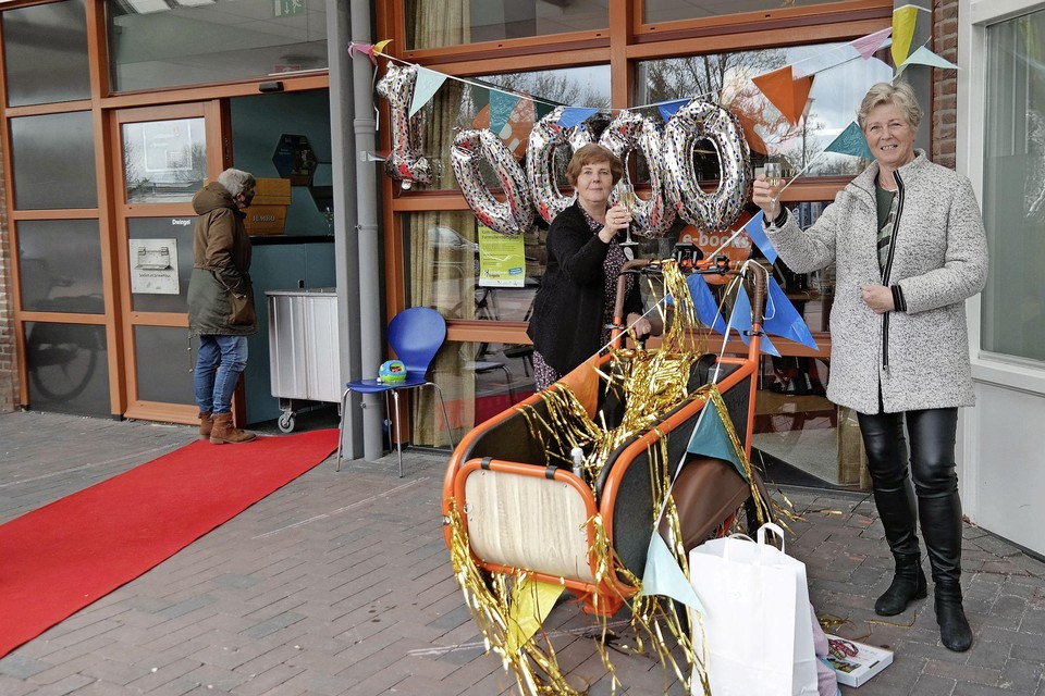 Angela van der Horst (links), front office medewerker van de bibliotheek in De Goorn zet mevrouw Van Hees uit Berkhout in het zonnetje gezet ter ere van de 10.000e verrassingstas.