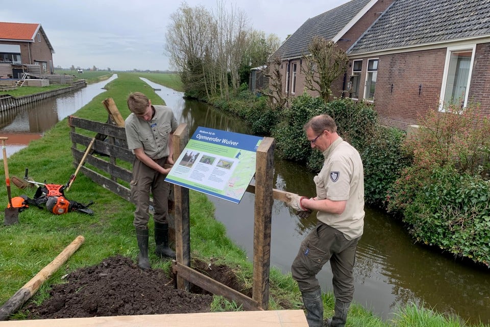 Medewerkers van Landschap Noord-Holland installeren het informatiebord bij de Opmeerder Wuiver. Volgens critici loopt het natuurgebied serieus gevaar door woningbouw.