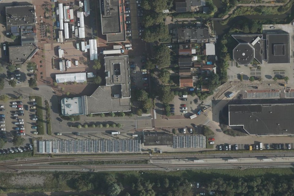 Een luchtfoto van het stationsgebied in Bovenkarspel. Onder het station, links het pand van de Rabobank en midden boven het station het kantoor en werkplaats van De Woonschakel. De Stationslaan ligt er tussenin.