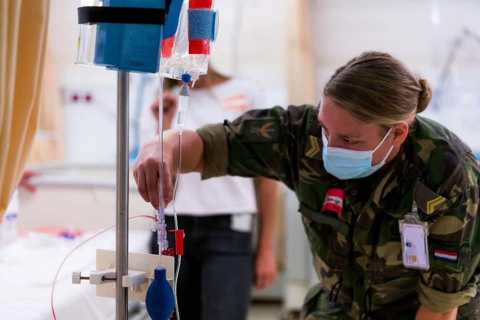 Een militair plaatst een infuus in een civiel ziekenhuis.
