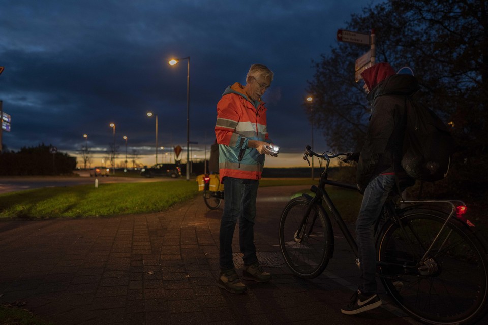 Vrijwilliger Piet Janssen geeft een fietslampje weg aan iemand die zonder licht rijdt.
