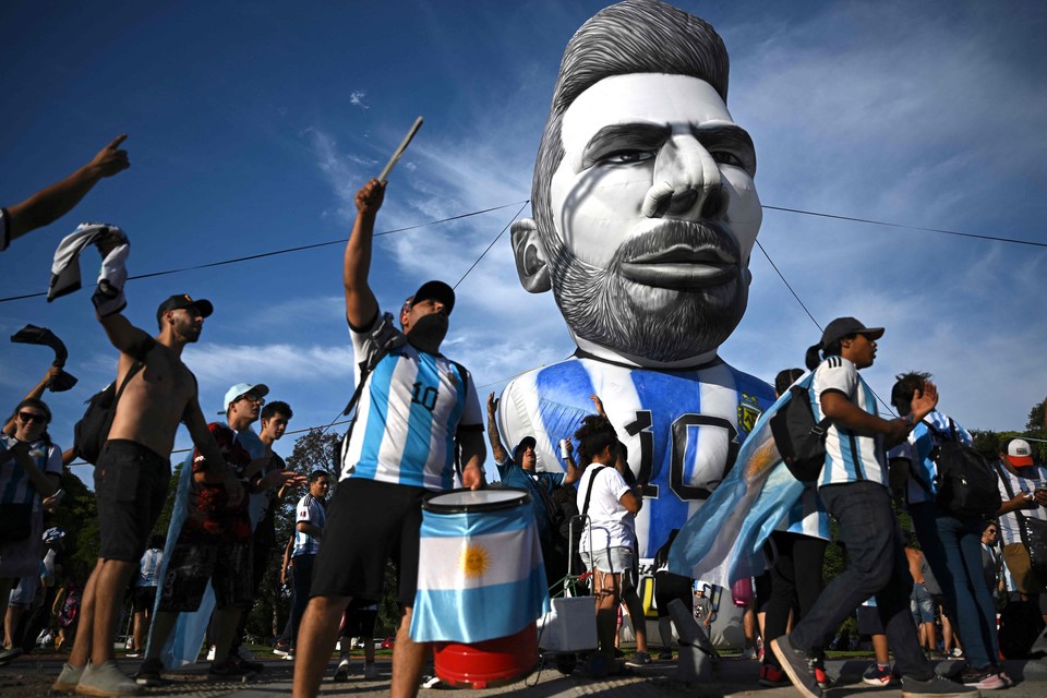 TOPSHOT - Fans of Argentina celebrate next to an inflatable depicting football star Lionel Messi nearby the live broadcast of the Qatar 2022 World Cup round of 16 football match between Argentina and Australia, at Francisco Seeber square, on December 3, 2022 in Buenos Aires. (Photo by Luis ROBAYO / AFP) fbl TOPSHOTS Horizontal