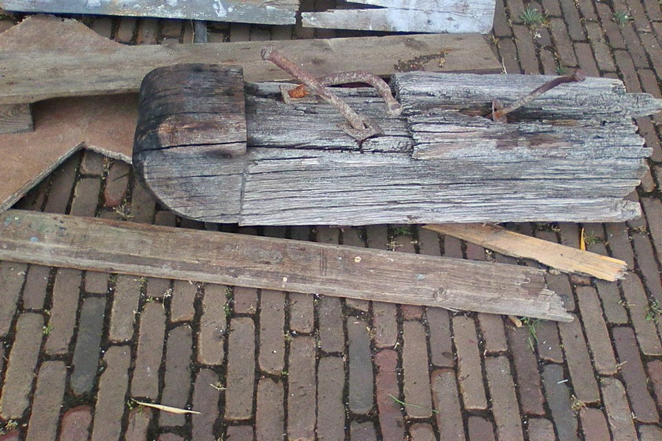 Het houten blok met metalen pennen en andere rotzooi die uit de haven is gevist.