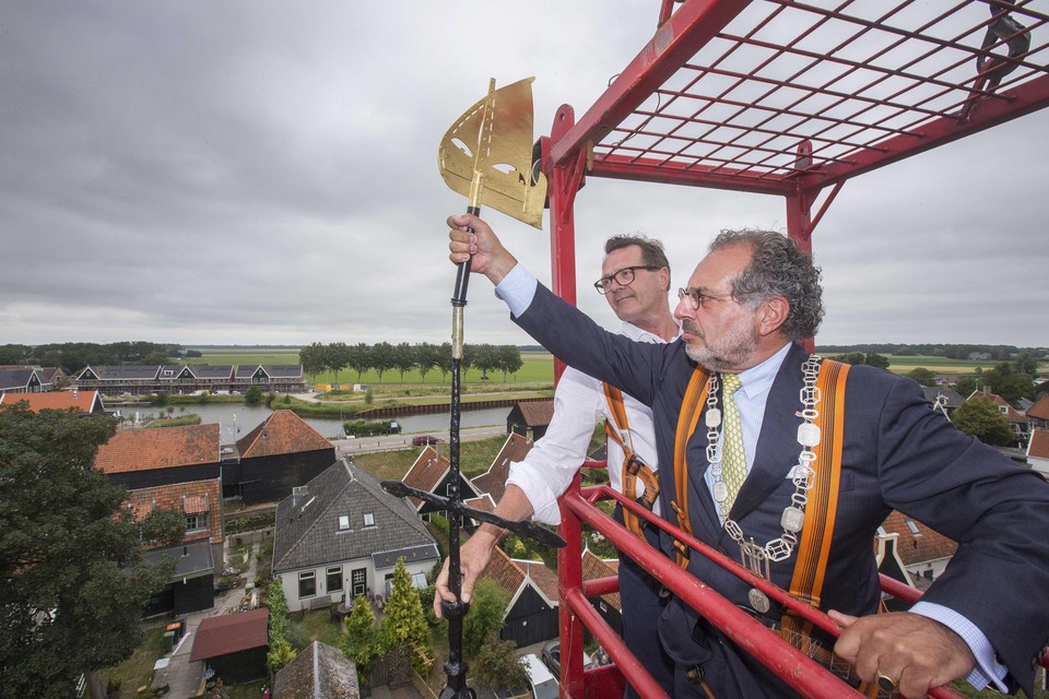 Burgemeester Jaap Nawijn zet de windvaan op de Laurenskerk, geholpen door C. Veld van bouwbedrijf Hoorn80 die de restauratie uitvoerde.