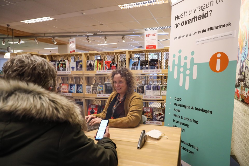 Bibliotheekmedewerker Eva de Jager geeft uitleg aan een bezoeker die moeite heeft met digitale vragen van de overheid.