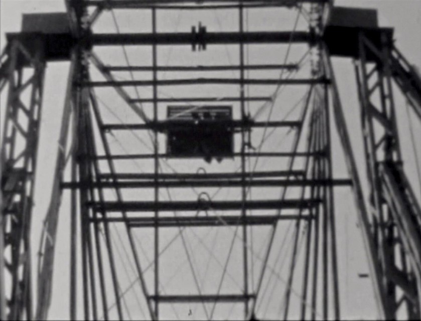Artistieke filmische opnamen van een draaiend reuzenrad dat helder afsteekt tegen een wolkeloze lucht.