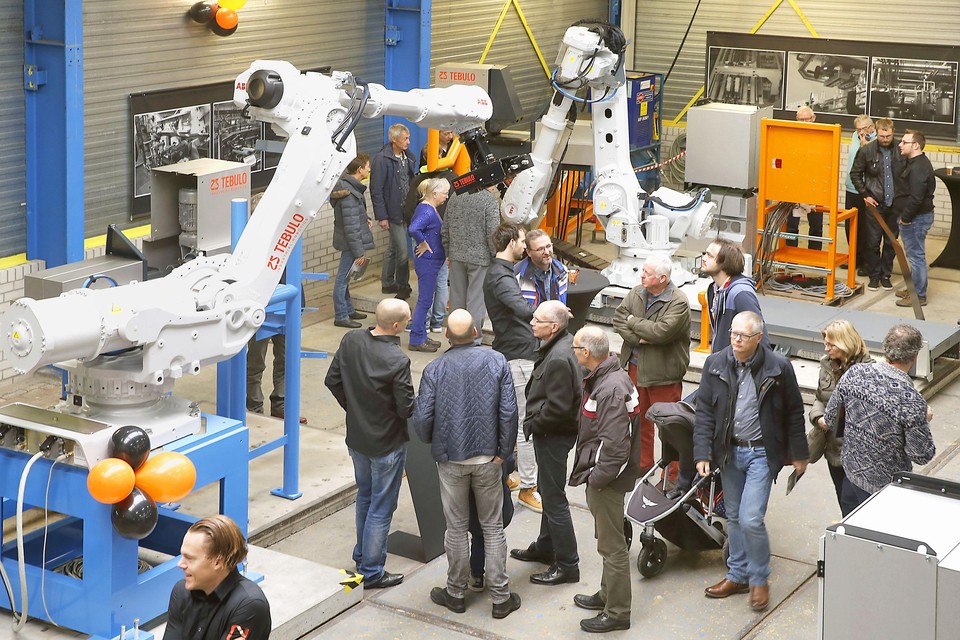 Bezoekers werpen geïnteresseerd een blik op de robots in de werkplaats van Tebulo.