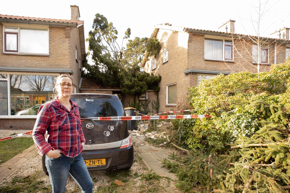 Tanja Koops voor haar huis, waar een hoge spar op viel. Haar auto kreeg ook flinke schade door de klap.