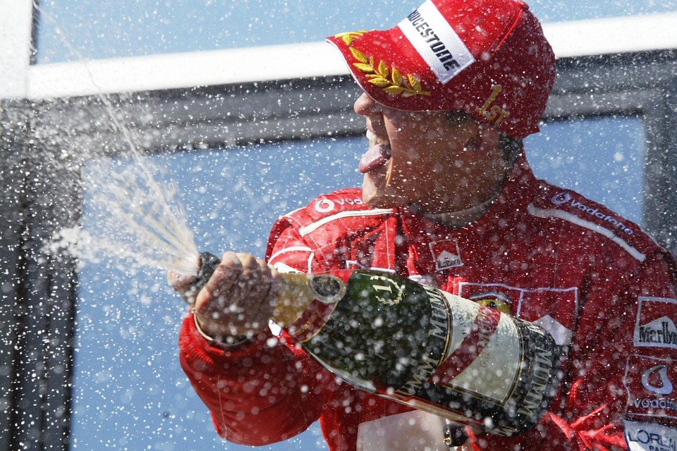 Michael Schumacher spuit de champagne van de winnaar. Een jaar eerder stond hij op hetzelfde podium als winnaar met tranen in zijn ogen.