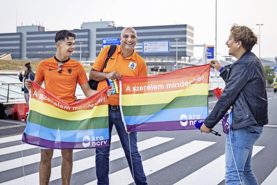 SCHIPHOL - Presentator Klaas van Kruistum overhandigt een voetbalfan een regenboogvlag op Schiphol, tijdens opnames voor tv-programma Klaas kan alles.