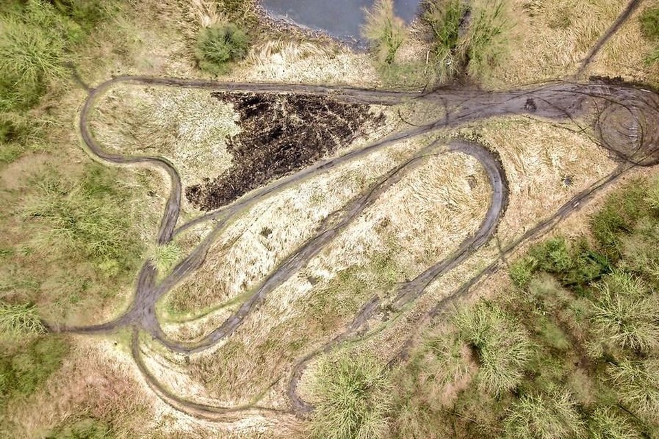 Dronebeelden van sporen van motorcrossers, donkere vlak is aangetast door brandstichting.