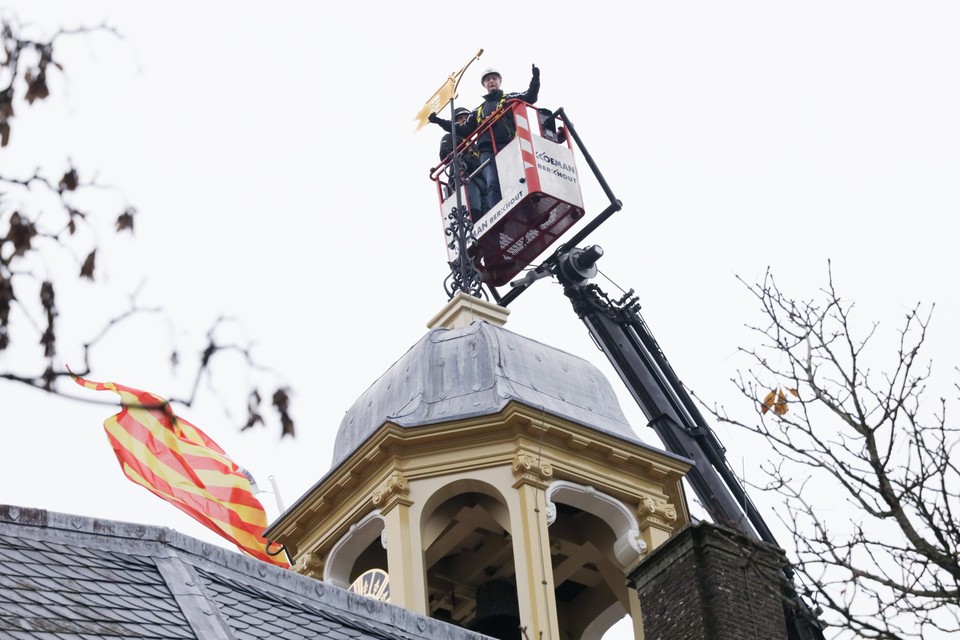 Wethouder Win Bijman plaatst de gouden windvaan op de toren van de Koepoort.