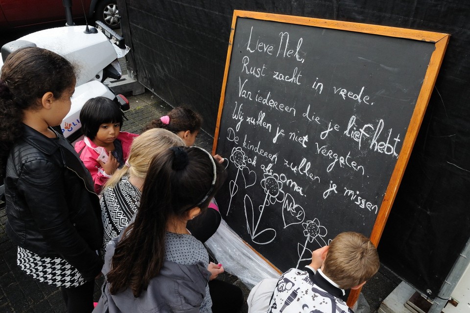 Kinderen tekenen bloemen en hartjes op het schoolbord voor de woning van oma Nel. Foto Maurice Amoureus
