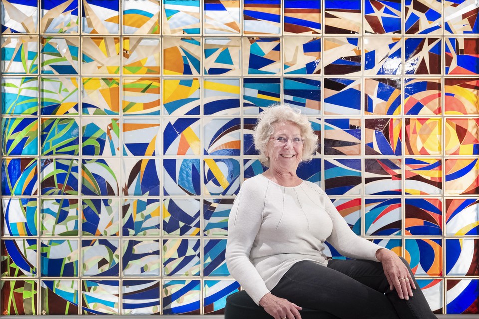 Martie Vink, die na 12 jaar afscheid neemt als voorzitter van de stichting Dorpscentrum Spaarndam, voor het glaskunstwerk van Michiel de Boer in de hal.