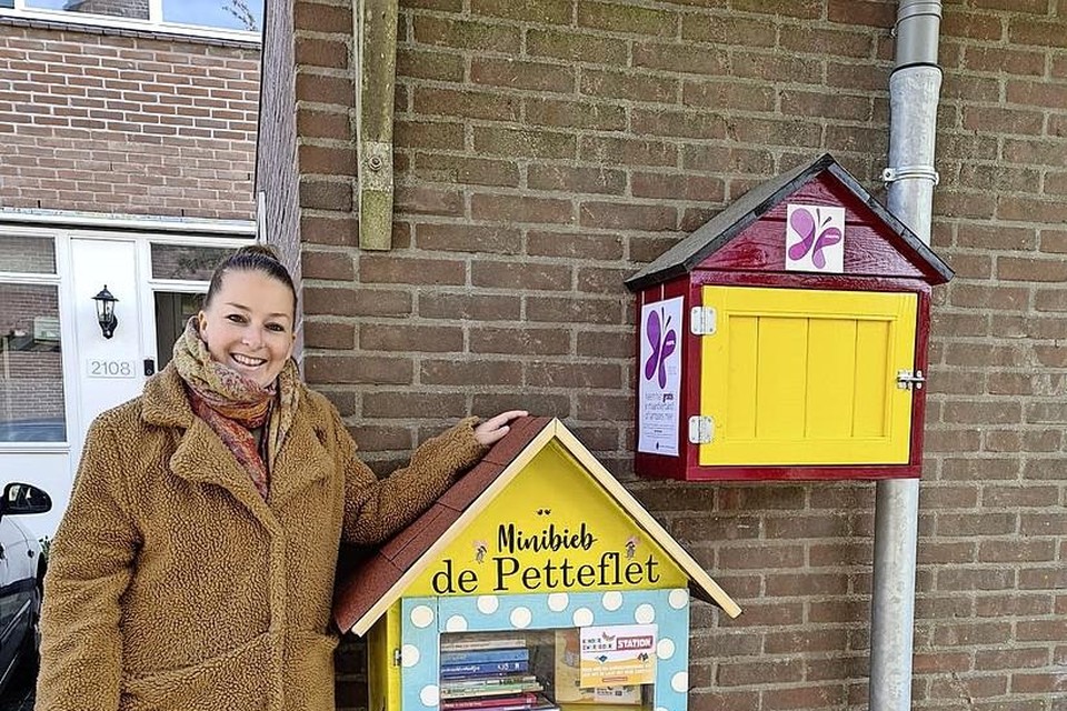 Jasmijn Wijnants bij de kastjes aan de buitenmuur van haar woning.Het ene is gevuld met kinderboeken, het andere met gratis maandverband en tampons.
