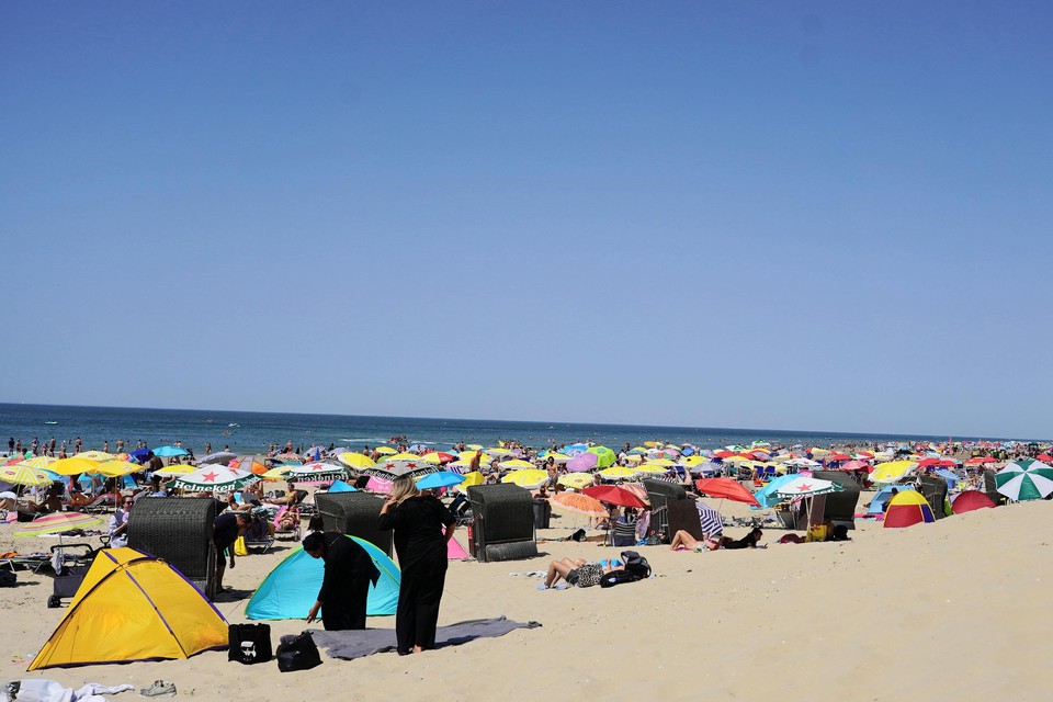 Onder het bonte kleurenpalet van opgestoken parasols vinden de strandgasten de broodnodige schaduw.
