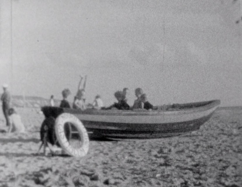 De hele dag speelden de kinderen in het zand. Hier hebben ze de paraat liggende roeiboot van de reddingbrigade veroverd. Op de voorgrond de lier met de lijflijn en de reddingsboei van Noordzee-Bad-Castricum.