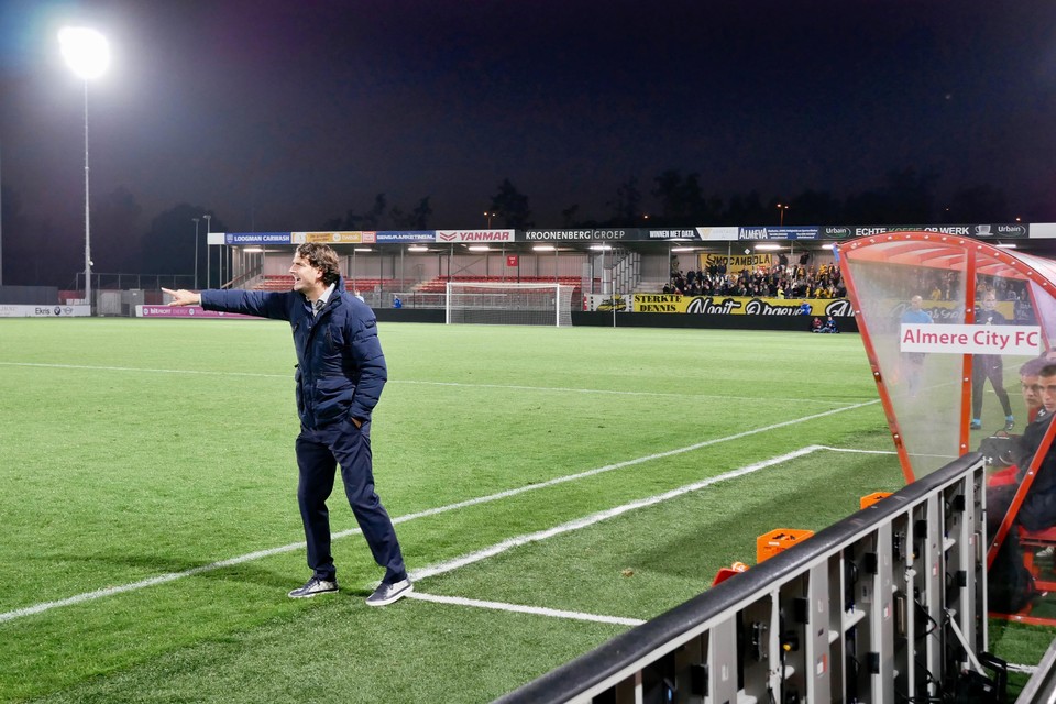Staand voor de dug-out van Almere City geeft Jong AZ-trainer Koen Stam aanwijzingen aan zijn spelers.