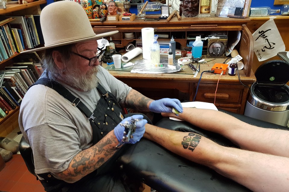 Henk Schiffmacher tatoeëert het Snertpop-logo op de kuit van Jasper.