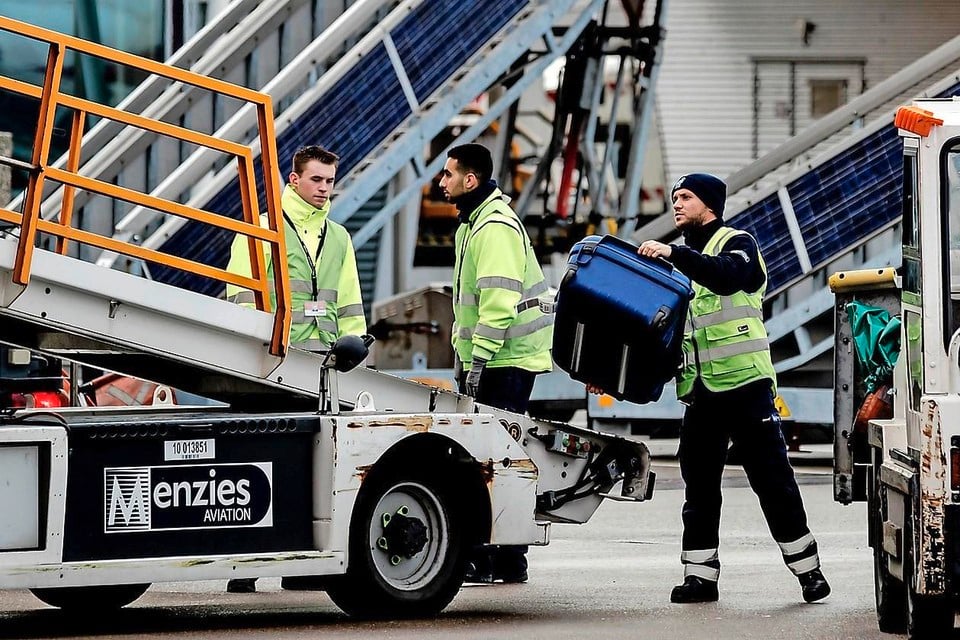 Bagage wordt geladen in een vliegtuig op het platform van Schiphol.