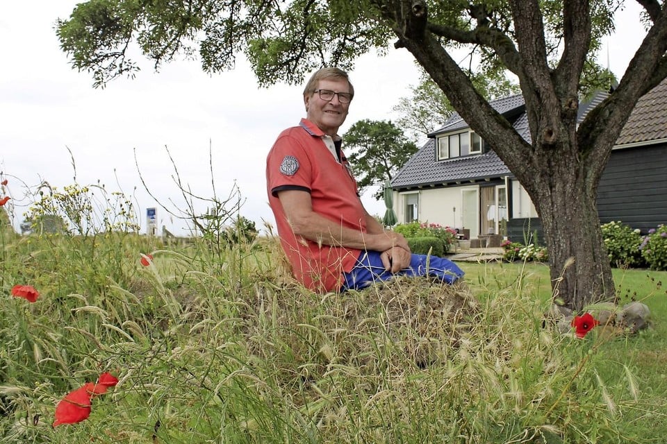 Simon Bakker op een tuinwal bij zijn huis onder de perenboom die zijn overgrootvader ooit geplant heeft.