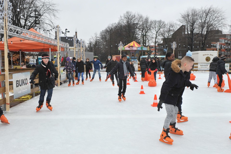 Scholieren schaatsen over de ijsbaan op het Stationsplein.