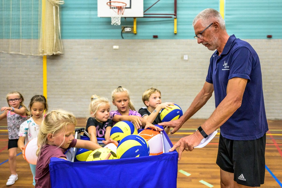 Jaap Conijn deelt volleyballen uit aan de deelnemers.