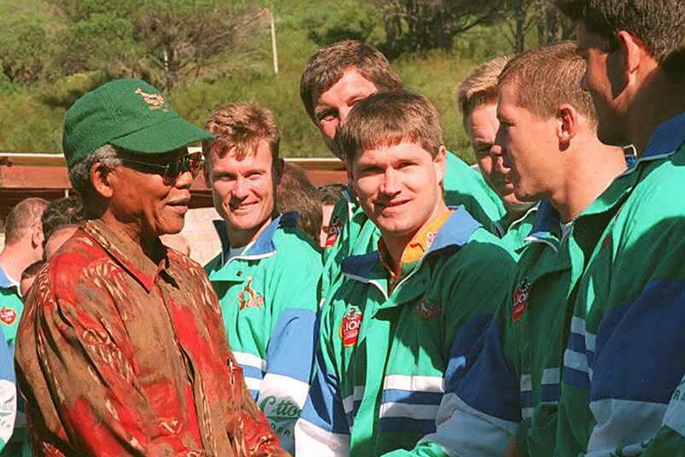 President Nelson Mandela schudt de spelers van het Zuid-Afrikaans rugbyteam de hand.