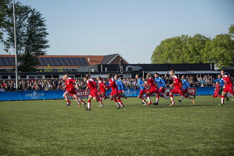 De spelers van Purmersteijn rennen uitzinnig van vreugde richting doelman Tim Elmers, die de laatste penalty op de lat boven hem zag belanden.