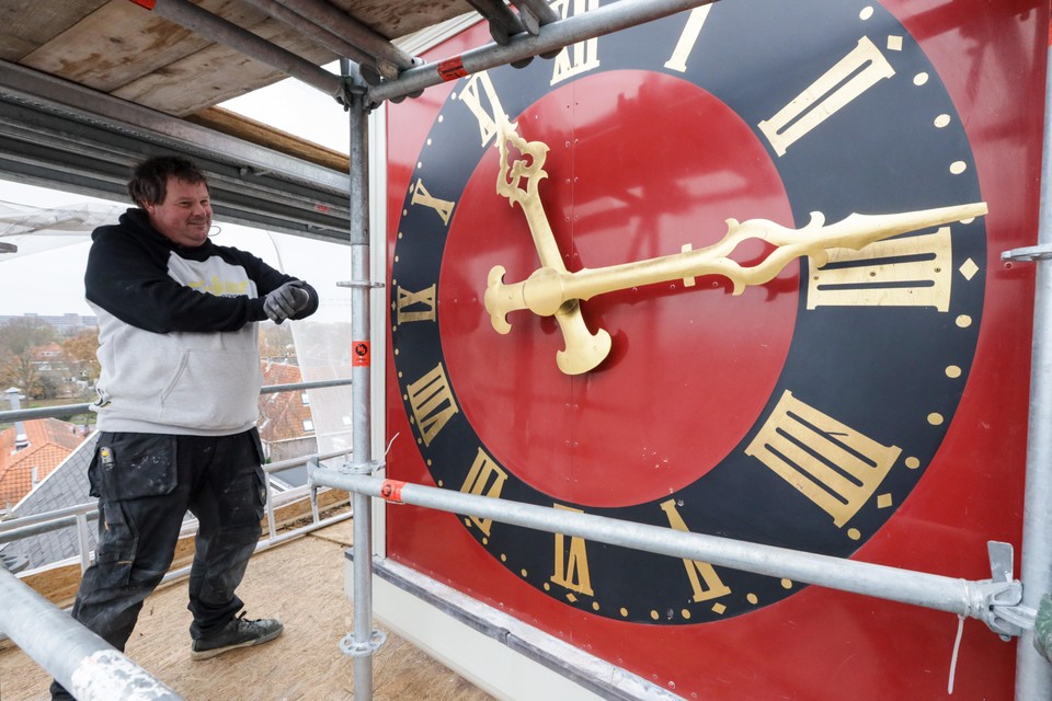 Bouwvakker Fabian Bakker bekijkt aan de hand van zijn eigen horloge of het geveluurwerk van de Noorderkerk welk goed staat.