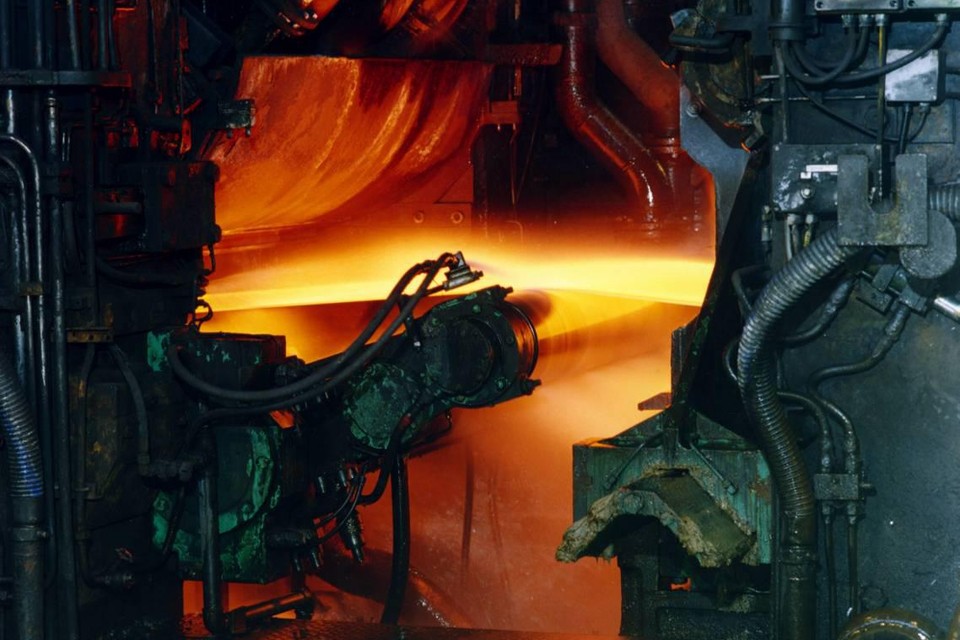Een plak gloeiend staal wordt dungewalst bij Tata Steel.