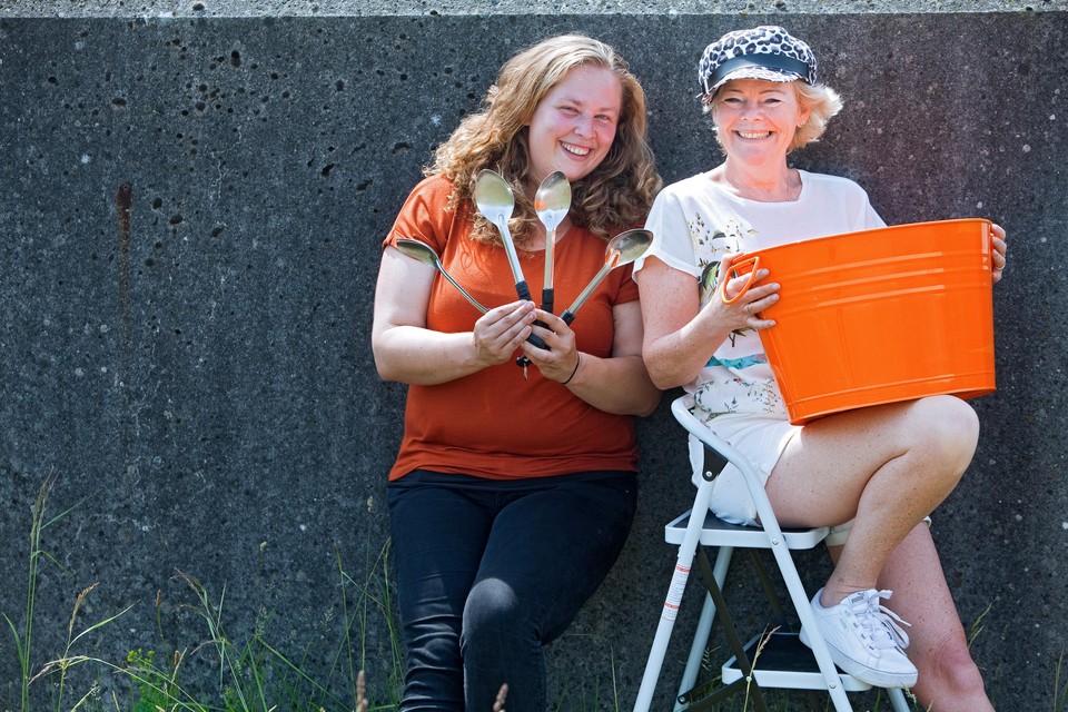 Stella van Lieshout (links) en Anne Marie Belterman. De leden van de Gemeenschap eten aan een lange tafel, alleen maar met lepels. Oranje is de kleur van hun huisjes in de Luwte.