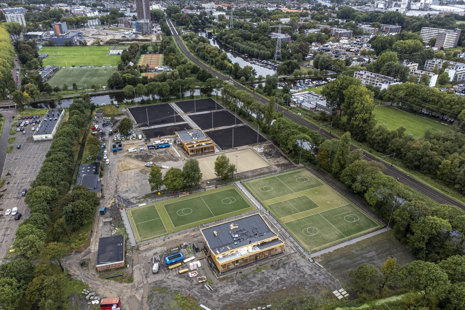 Op de voorgrond de korfbalvelden en het clubhuis in aanbouw. Daarachter de nog zwarte tennisbanen. De sportvelden over het water heen gaan wijken voor woningbouw.