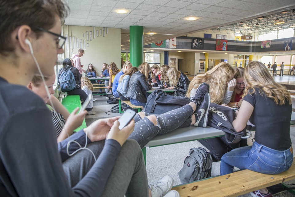Leerlingen vermaken zich met hun mobiele telefoon in de agora van Lyceum aan Zee.