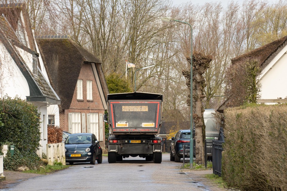 Vrachtwagens voor de afvoer van puin van het Ocrietterrein kruipen door het smalle straatje in Eembrugge.