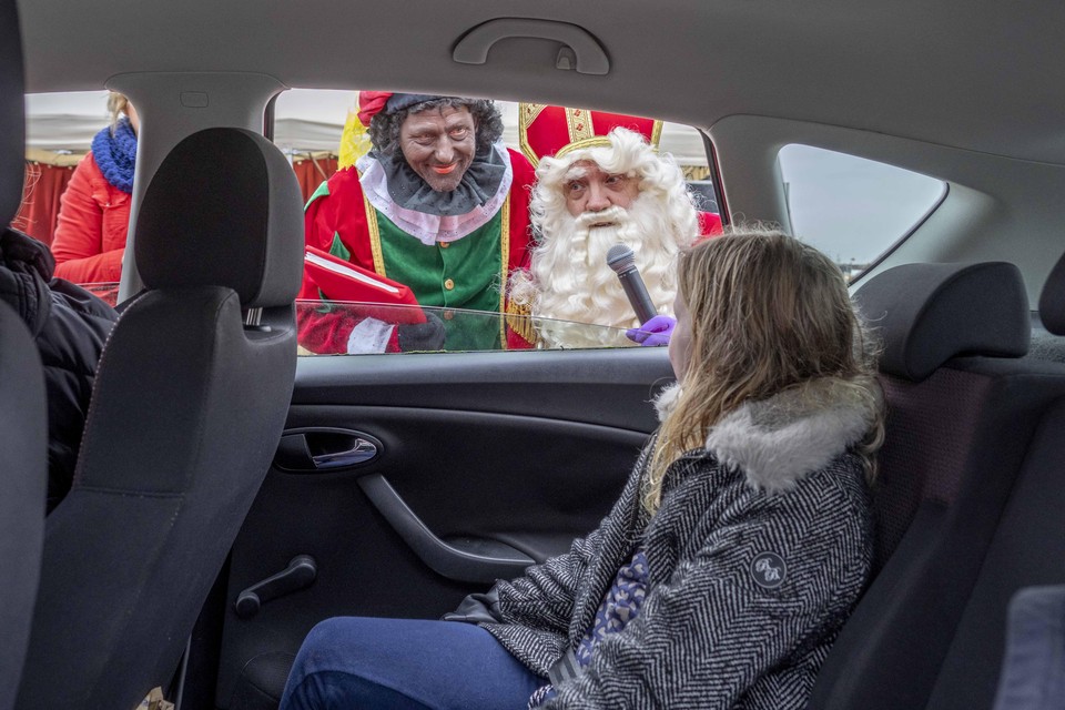Sinterklaas en Piet praten met kinderen, die lekker op de achterbank kunnen blijven zitten.