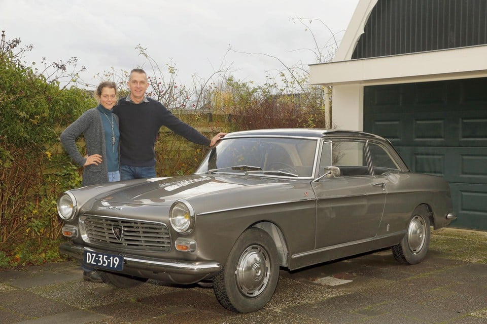 Carla en Sander Maij poseren bij hun gerestaureerde Peugeot 404 coupé uit 1964.