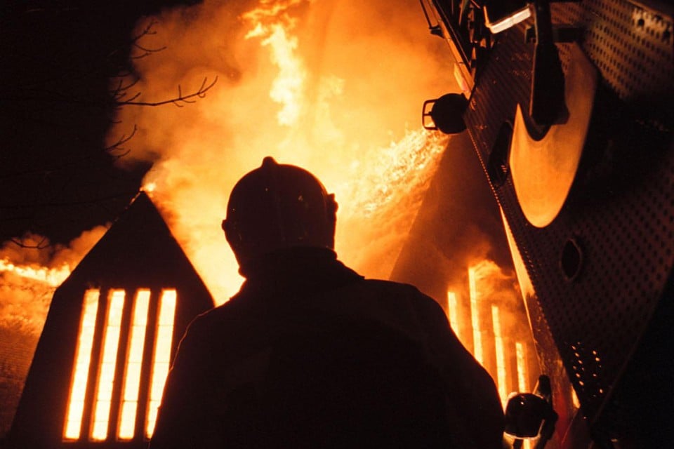 Een brandweerman staat bij de brand in de Koningkerk op 23 maart 2003. Drie brandweerlieden kwamen die dag om het leven.