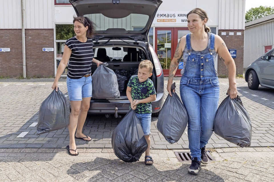 Marcia van Diepen, zoon Daan en Bianca Hofmeijer sjouwen de zakken naar de Kinderkledingbank.