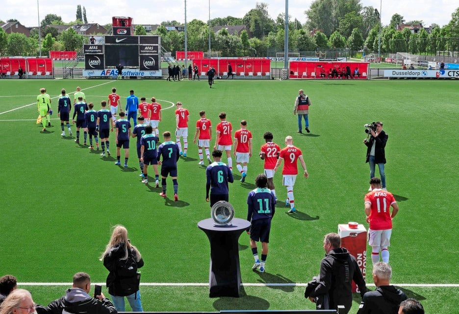 De elftallen komen het veld op, met op de voorgrond de kampioensschaal.