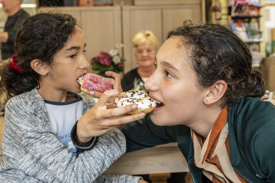 De zusjes Amina (9) en Khaoula (13) gunnen elkaar een hapje van hun donut.