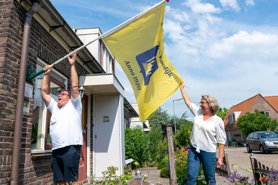 Bewoners Fred van den Akker en Nel Ruig steken de vlag in de vlaggenhouder. Oostwijk blijft bestaan.