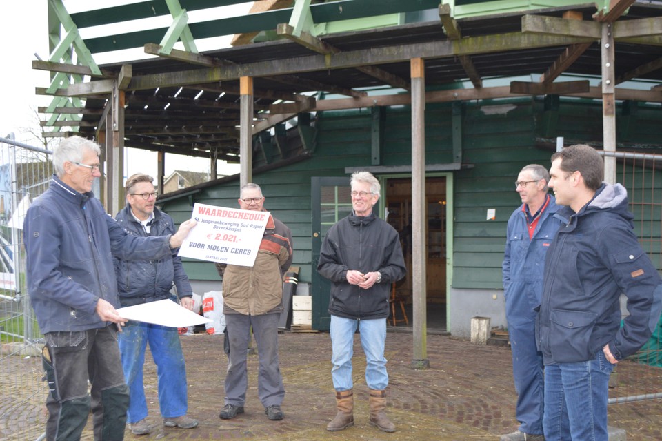 De molenaars van molen Ceres met hun cheque van de Stichting Jongerenbeweging Oud Papier, met uiterst rechts voorzitter Richard Bakker van deze stichting.
